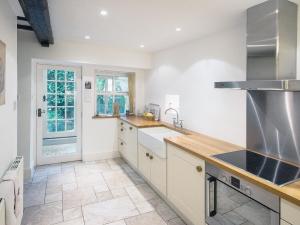 a large kitchen with white cabinets and a sink at Barbican Cottage in Middleham