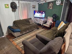 a living room with a couch and a tv at Chácara Nhá Chica - Roseira - Aparecida - a 8km do Santuário Nacional in Aparecida