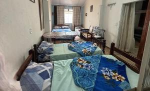 a room with four beds with blue comforters on them at Chácara Nhá Chica - Roseira - Aparecida - a 8km do Santuário Nacional in Aparecida