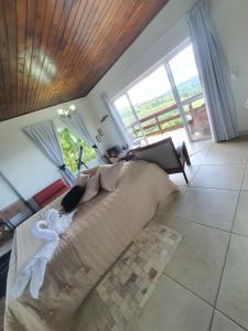 a living room with a large couch and large windows at Chalé 3 com Hidro Acima das Nuvens in Campos do Jordão