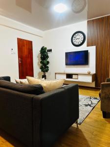 ハボローネにあるRibbon 210's Two bedroom apartmentのリビングルーム(ソファ、壁掛け時計付) +20枚の写真