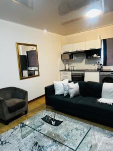 ハボローネにあるRibbon 210's Two bedroom apartmentのリビングルーム(黒いソファ、椅子付)