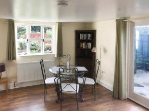 a dining room with a table and chairs and windows at Tiptoe in Steeple Ashton