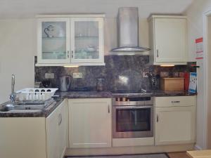 a kitchen with white cabinets and a sink at Minafon in Penmaen-mawr +7 photos