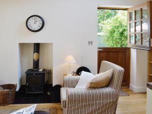 a living room with a fireplace and a clock on the wall at Minafon in Penmaen-mawr