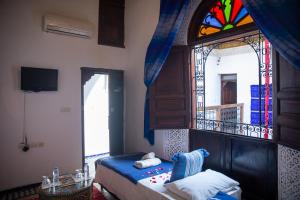 a bedroom with a bed and a stained glass window at Riad LalaMoune in Fez