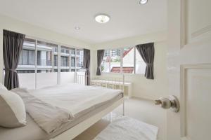 a white bedroom with a bed and a window at UrbanLoft Sukhumvit 5BR Bangkok 5 min BKK Hospital in Ban Sam Ngam