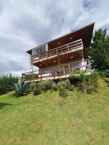 a house sitting on top of a grassy hill at Chalé 3 com Hidro Acima das Nuvens in Campos do Jordão