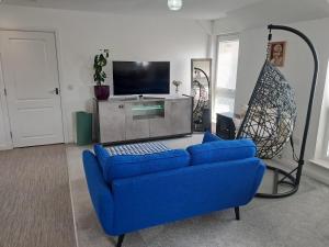 un soggiorno con un divano blu e una TV di Detached Home in Bishopton a Bishopton