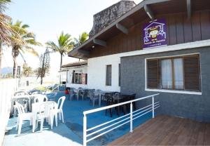 a restaurant with white chairs and tables on a deck at Pousada do Bill in Peruíbe