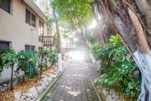 a walkway between two buildings with trees and plants at Suites Lafragua in Veracruz