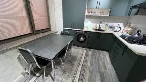 a kitchen with a table and chairs and a washing machine at Квартира APPETIT in Andijan