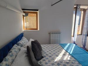 a bedroom with a bed with blue sheets and a window at Antico Arco in Montalto Ligure +14 photos