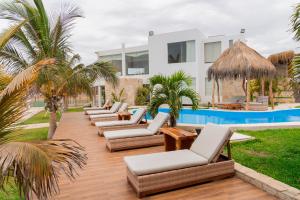 a row of chaise lounges and chairs next to a pool at Hotel Beso de Sal Resort in Colán