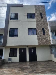 a tall building with two black doors in front of it at Apartaestudio 302 Acogedor y Moderno Tulua in Tuluá