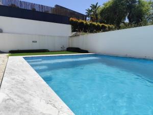 une piscine devant un mur blanc dans l'établissement Casa Alto das Vinhas, à Sesimbra