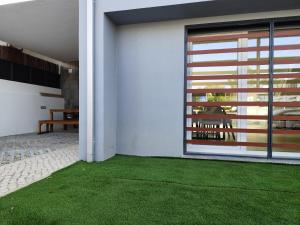a house with a green lawn in front of a door at Casa Alto das Vinhas in Sesimbra