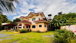 a large yellow house with a green yard at Chateau La Princesa with cozy garden & bar in Puerto Princesa City