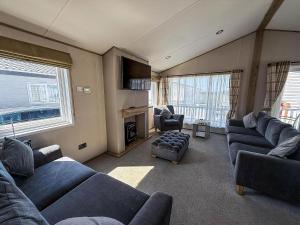 a living room with blue couches and a tv at Stunning 3 Bedroom Lodge With Decking & Wifi In Essex Ref 44036G in Great Oakley