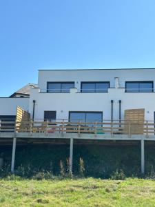ein weißes Gebäude mit Holzbänken auf einem Pier in der Unterkunft La Vallée des Biches G2 in Saint-Martin-Boulogne