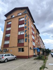 a building with a car parked in front of it at Apartament Sarah in Oţelu Roşu +1 photo