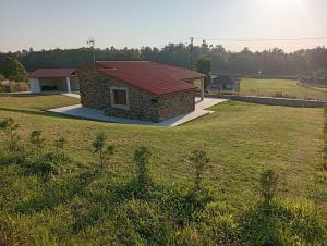 a small building with a red roof on a field at Eira do Xastre in Brocos