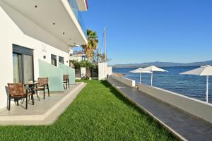 a patio with chairs and tables and the water at Vista Paraiso Inn in Nea Potidaea