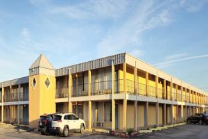 a yellow building with cars parked in a parking lot at Castle inn & suites by OYO Lawton in Lawton