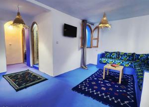 Sala de estar azul con sofá y mesa en Casa Autiui, en Chefchaouen