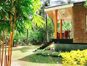 a house with a porch with a table and chairs at Milk House Cottage in Udawalawe