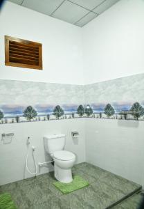 a bathroom with a toilet and a painting on the wall at EverGreen Resort Udawalawe in Udawalawe