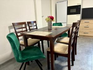 a dining room table with green chairs and a vase of flowers at Luna Apartmán in Strekov