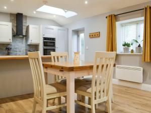 a kitchen and dining room with a wooden table and chairs at Bumble Cottage in Cockermouth