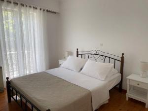 a bedroom with a bed with white sheets and a window at Philoxenia Apartments 2 in Samos