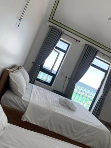 Phú HiệpにあるBien Xanh Homestayのベッドが2つと窓が2つある寝室