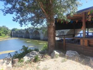 a tree next to a river with a bridge at Hotel Restaurant du Pont de Ners in Boucoiran-et-Nozières