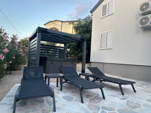 a group of chairs sitting on a patio next to a building at Villa EnVi in Novalja