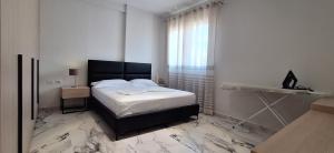 a white bedroom with a bed and a window at White Palace in Vlorë