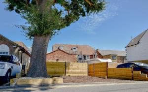 a tree sitting next to a wooden fence at Holdens Cottage in Whitstable