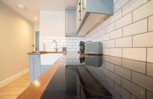 a kitchen with white tiles on the wall at Holdens Cottage in Whitstable