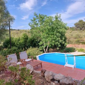 a swimming pool with two chairs and a table next to at Il Verdone in Usini