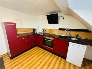 a kitchen with red cabinets and a sink at Apartment mit Balkon an der Mosel in Koblenz-Güls in Koblenz