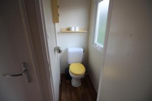a small bathroom with a toilet with a yellow lid at Land's Hause Bungalows par La Conciergerie Française Emplacement S4 in Pataias