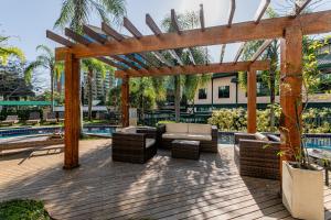 a wooden pergola with couches and chairs next to a pool at Flat Barra Residence-4 pessoas-Fa1204-3 in Rio de Janeiro