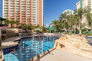 a large swimming pool with chairs and a large building at Flat Barra Residence-4 pessoas-Fa1204-3 in Rio de Janeiro