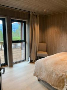 a bedroom with a bed and a chair and windows at Moderne og romslig familiehytte i Stryn in Stryn