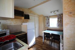 eine kleine Küche mit einem weißen Kühlschrank und einem Tisch in der Unterkunft Land's Hause Bungalows par La Conciergerie Française Emplacement S5 in Pataias + 1 Foto