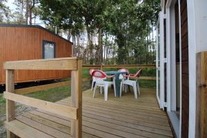 eine Holzterrasse mit einem Tisch und Stühlen darauf in der Unterkunft Land's Hause Bungalows par La Conciergerie Française Emplacement S5 in Pataias