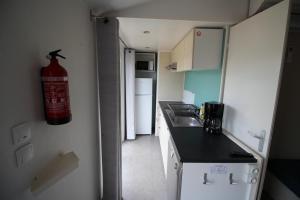 eine kleine Küche mit einem Feuerlöscher an der Wand in der Unterkunft Land's Hause Bungalows par La Conciergerie Française Emplacement S6 in Pataias + 2 Fotos