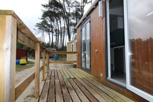 eine Holzterrasse neben einem Haus in der Unterkunft Land's Hause Bungalows par La Conciergerie Française Emplacement S6 in Pataias